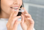 Close-up of a woman putting in an Invisalign tray for her top teeth